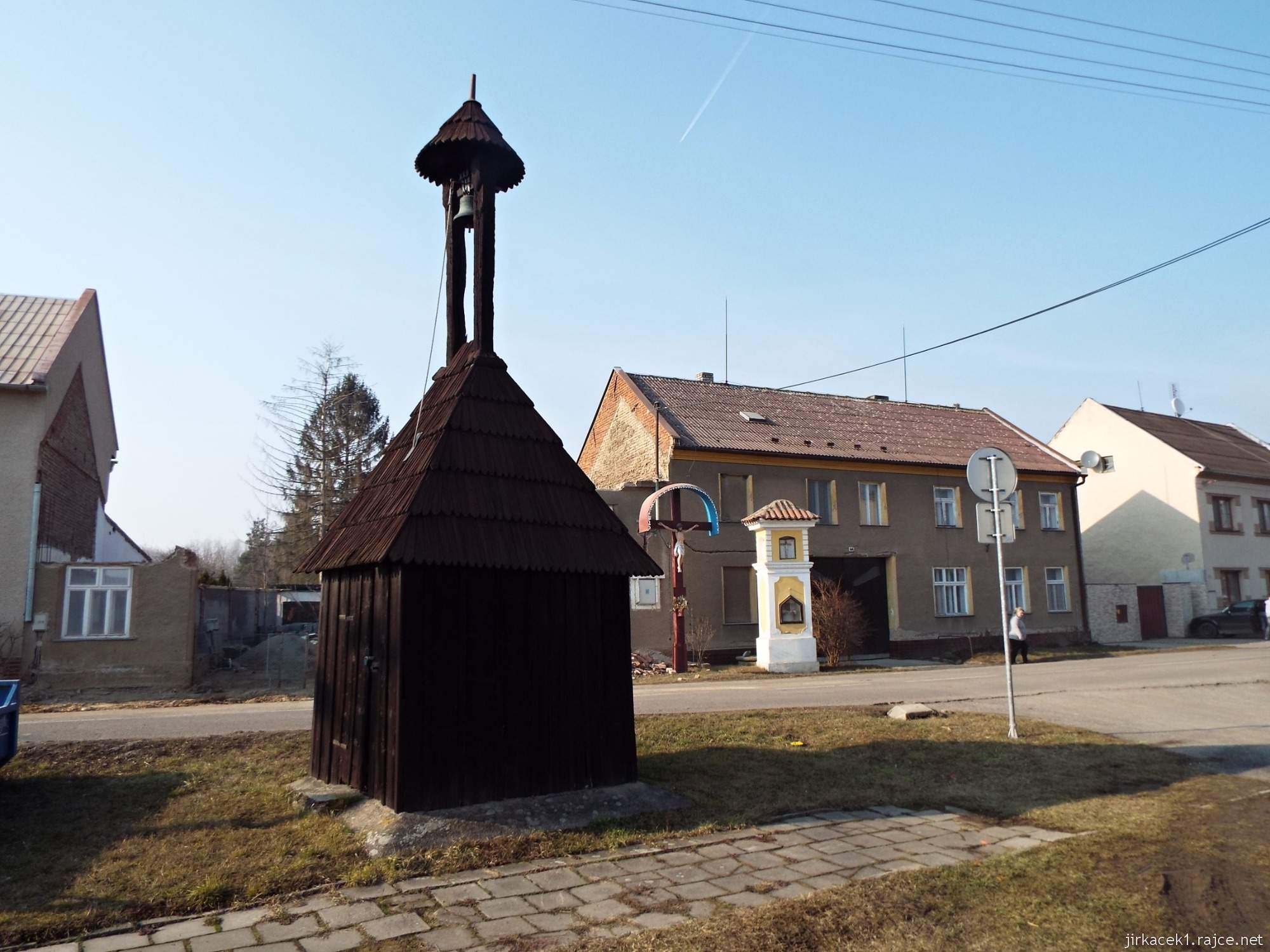 G - Lhota nad Moravou 10 - náves - dřevěná zvonička a za ní Boží muka